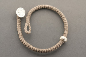 Gray textured bracelet with silver accents on a gray background