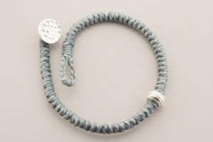 Gray textured bracelet with silver accents on a gray background