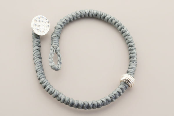 Gray textured bracelet with silver accents on a gray background