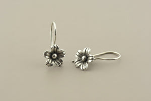 Pair of silver flower-shaped earrings on a gray background