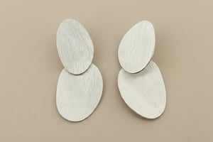 Pair of silver earrings on a gray background