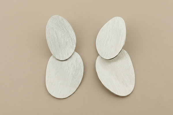 Pair of silver earrings on a gray background