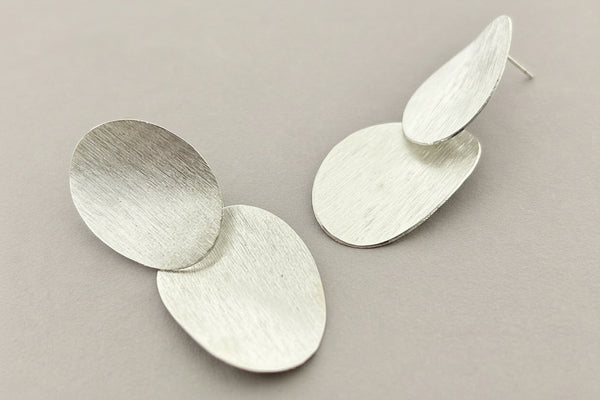 Pair of silver earrings on a dark gray background
