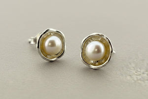 Pair of pearl stud earrings on a dark gray background
