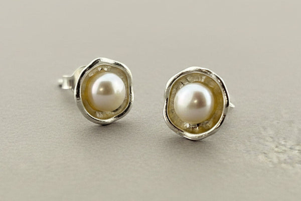 Pair of pearl stud earrings on a dark gray background