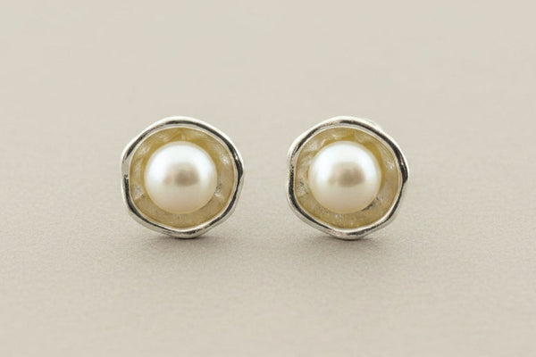 Silver earrings with pearls on a gray surface