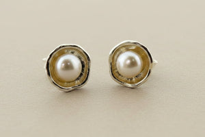 Pair of pearl stud earrings on a gray background