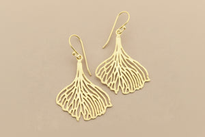 Gold leaf-shaped earrings on a gray background