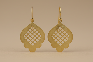 Gold earrings with intricate designs on a beige background