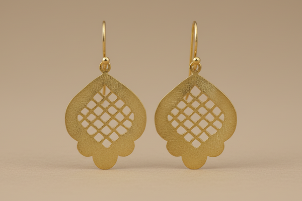Gold earrings with intricate designs on a beige background