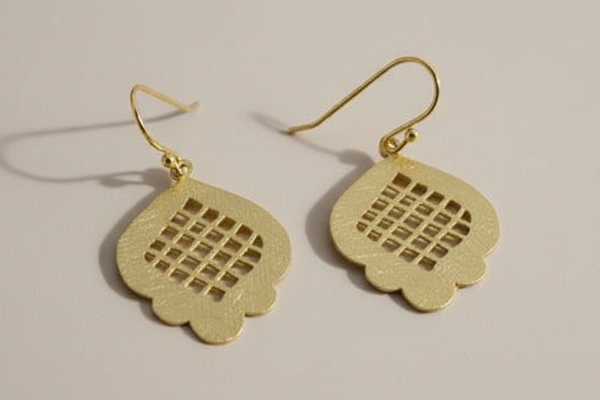 Gold earrings with intricate design on a beige background